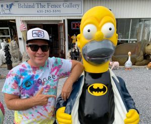 Joel in Apogee tie-dye standing next to Homer Simpson Batman statue